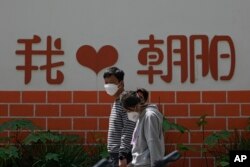 北京朝阳区两个带着口罩的居民去排队做新冠核酸检测。（2022年5月11日）
