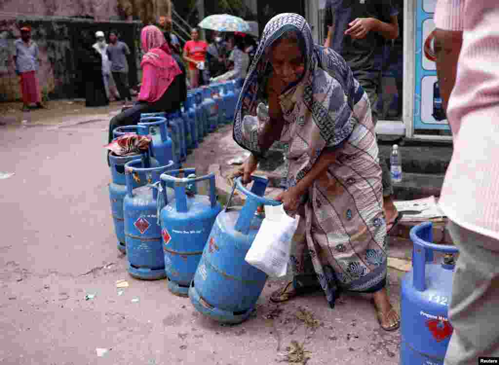 A woman moves a gas tank as she waits in line near a distributor amid the country&#39;s economic crisis, in Colombo, Sri Lanka.