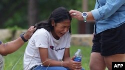 A girl cries, comforted by two adults, outside the Willie de Leon Civic Center where grief counseling will be offered in Uvalde, Texas, May 24, 2022. A teenage gunman killed 18 young children in a shooting at an elementary school in the city on Tuesday, i
