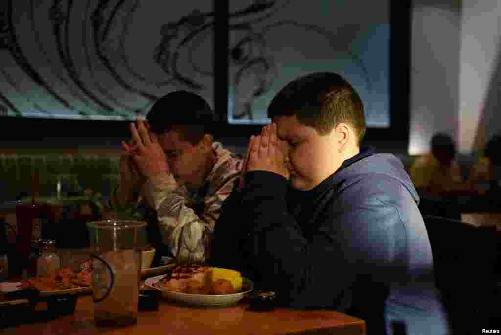 Brothers Julius and Aidan Garza say a prayer in honor of their father at a restaurant in Converse, Texas, March 30, 2022. &#39;Never forget&#39; Not long ago as he walked home from his school bus stop, a blue jay appeared in Aidan Garza&#39;s path. It was so beautiful, &quot;I didn&#39;t think it was real,&quot; he said. &quot;It was so calm, not feisty like the other ones.&quot; Aidan swears that his dad has taken to inhabiting blue jays to keep watch over him. The boy peppers his conversations about his dad with the lessons he has learned from therapy, which he and his brother have received since their dad died, on how to confront his grief. In talking about his heart and how much he should be thinking about his dad, Aidan says &quot;we always got to save a little spot for him - and a big spot for emotions.&quot; Aidan&#39;s brother, Julius, has trouble with that one. &nbsp;