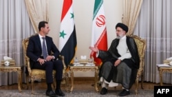 A handout picture provided by the Iranian presidency on May 08, 2022 shows Iranian President Ebrahim Raisi (R) receiving Syrian President Bashar al-Assad in the capital Tehran. (Photo by Iranian Presidency/AFP)