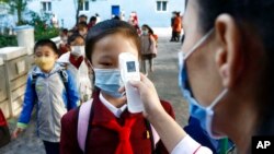 지난해 10월 북한 평양의 한 학교에서 교사가 등교하는 학생의 체온을 재고 있다.