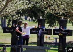 Pengunjung salib peringatan yang didedikasikan untuk 13 orang yang terbunuh dalam penembakan di Columbine High School pada tahun 1999, di Littleton, Colorado, 20 April 2014 (AP/Brennan Linsley)