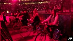 Concertgoers ride stationary bikes during Coldplay's Music of the Spheres world tour on Thursday, May 12, 2022, at State Farm Stadium in Glendale, Ariz. (Photo by Rick Scuteri/Invision/AP)