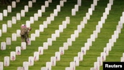 A soldier of the 3rd U.S. Infantry Regiment places flags on headstones ahead of Memorial Day at more than 260,000 headstones at Arlington National Cemetery, in Arlington, Virginia, U.S., May 26, 2022. 