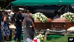 People pay their final respects to Irma Garcia and husband, Joe Garcia, during a burial service at Hillcrest Cemetery, June 1, 2022, in Uvalde, Texas. Irma Garcia was killed in last week's elementary school shooting. Joe Garcia died two days later.