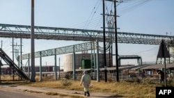 FILE - A miner walks past the entrance of the Sibanye-Stillwater platinum mine in Marikana, South Africa, on May 15, 2020. 