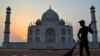 A worker sweeps the ground at the Taj Mahal at sunrise in Agra on May 12, 2022. 