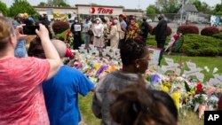 People gather around a memorial for the victims of the Buffalo supermarket shooting outside the Tops Friendly Market, May 21, 2022, in Buffalo, N.Y.