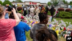 People gather around a memorial for the victims of the Buffalo supermarket shooting outside the Tops Friendly Market, May 21, 2022, in Buffalo, N.Y.