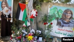 FILE - A Palestinian woman takes pictures at the scene where Al Jazeera reporter Shireen Abu Akleh was shot dead during an Israeli raid, in Jenin, in the Israeli-occupied West Bank, May 17, 2022.