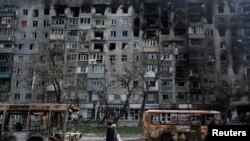 Місцевий житель проходить вулицею повз згорілі автобуси в Маріуполs, Україна, 19 квітня 2022 року. REUTERS/Олександр Єрмоченко.