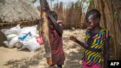 Dua anak sedang menumbuk bahan makanan di Ganyiel, Kabupaten Panyijiar, Sudan Selatan. Menurut PBB, hampir tiga juta anak Sudan di bawah usia lima tahun mengalami kekurangan gizi akut. (Foto: AFP)