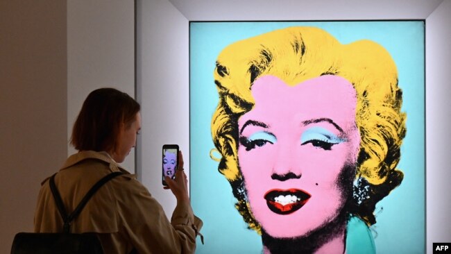A woman takes a photo of Andy Warhol's 'Shot Sage Blue Marilyn' during Christie's 20th and 21st Century Art press preview at Christie's New York on April 29, 2022, in New York City.