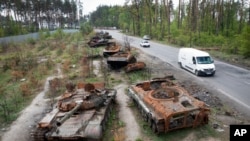 Cars pass by destroyed Russian tanks in a recent battle against Ukrainians in the village of Dmytrivka, close to Kyiv, Ukraine, May 23, 2022.