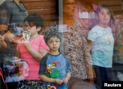 Los niños miran a través de una ventana de vidrio desde el interior del Centro Cívico Ssgt Willie de Leon, a donde fueron transportados desde la Escuela Primaria Robb después de un tiroteo, en Uvalde, Texas, el 24 de mayo de 2022.