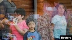 Los niños miran a través de una ventana de vidrio desde el interior del Centro Cívico Ssgt Willie de Leon, a donde fueron transportados desde la Escuela Primaria Robb después de un tiroteo, en Uvalde, Texas, el 24 de mayo de 2022.