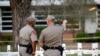 Texas Department of Public Safety officers stand in front of a memorial outside Robb Elementary school, after a gunman killed nineteen children and two teachers, in Uvalde, Texas, May 26, 2022.