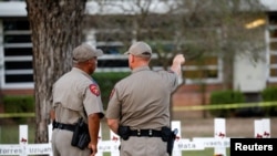 Texas Department of Public Safety officers stand in front of a memorial outside Robb Elementary school, after a gunman killed nineteen children and two teachers, in Uvalde, Texas, May 26, 2022.