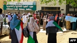 Protesters, some holding placards, rally outside a court in Sudan's capital of Khartoum, May 29, 2022, to support fellow demonstrators who have been charged with the killing of a senior police officer, as their trial opens in the capital Khartoum.