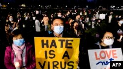 Sejumlah peserta aksi memegang lilin dan poster yang berisi ajakan anti kebencian dalam rangka menolak kekerasan dan kebencian terhadap warga Amerika keturunan Asia. Aksi tersebut digelar di Almansor Park, California, pada 20 Maret 2021. (Foto: AFP/Ringo Chiu)