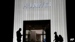 FILE - Shoppers pass by a Huawei store in Beijing, China, Thursday, Aug. 26, 2021.
