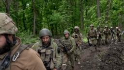 Ukrainian servicemen walk in the forest near a recently retaken village, north of Kharkiv, east Ukraine, May 15, 2022. 