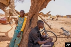 People find some shade under a tree in Djibo, Burkina Faso, May 26, 2022.