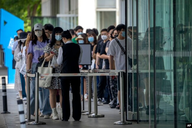 Employees wearing face masks wait to have their COVID-19 test results checked to enter an office building in the central business district in Beijing, Tuesday, May 31, 2022. (AP Photo/Mark Schiefelbein)