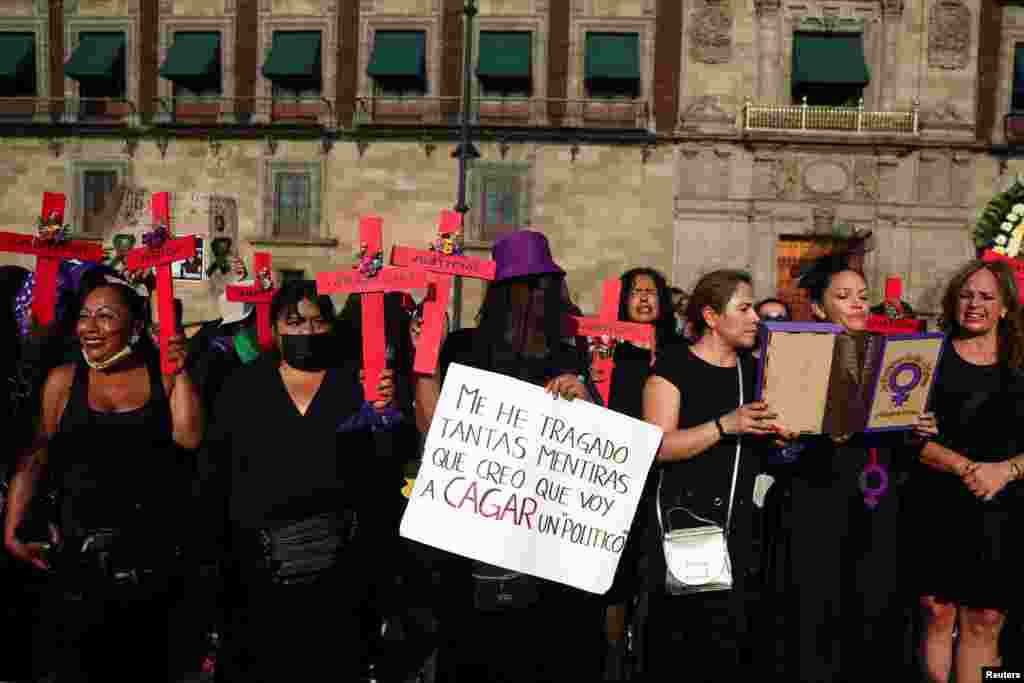 Las mujeres sostienen cruces y muestran un cartel con un mensaje contra los políticos durante una protesta contra la violencia de género frente al Palacio Nacional en la Ciudad de México.
