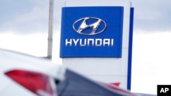 FILE - The company logo hangs over a long row of cars at a Hyundai dealership Dec.  20, 2020, in Centennial, Colo.