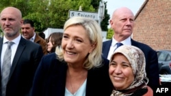 FILE - French far-right party Rassemblement National's (RN) leader Marine Le Pen, poses for a photograph as she visits a local flee market as she begins her campaigning for the upcoming legislative elections, in Henin-Beaumont, northern France, May 8, 2022.