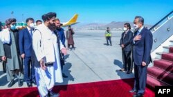 FILE - This handout photo released by the Taliban Foreign Ministry shows Taliban Foreign Minister Amir Khan Muttaqi, left, greeting China's Foreign Minister Wang Yi upon his arrival at the Kabul airport on March 24, 2022. 