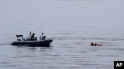 Tim penyelamat mengevakuasi korban yang mengapung di atas papan kayu saat mencari korban kapal kargo yang tenggelam di Selat Makassar, Minggu, 29 Mei 2022. (Foto: via AP)