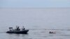 In this photo released by the National Search and Rescue Agency (BASARNAS), rescuers retrieve survivors floating on a wooden plank during a search for victims of a sinking cargo boat in the Makassar Strait, Indonesia, Sunday, May 29, 2022. (BASARNAS via AP)