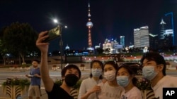 Residents pose for a selfie near the Oriental Pearl Tower along the bund, May 31, 2022, in Shanghai. Shanghai authorities say they will take major steps on Wednesday toward reopening China's largest city after a two-month COVID-19 lockdown.