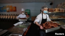 Staff members move cooked food outside a restaurant, after the city banned dine-in services amid the coronavirus disease outbreak in Beijing, China May 17, 2022. (REUTERS/Tingshu Wang)