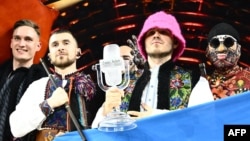 Members of the band "Kalush Orchestra" pose onstage with the winner's trophy and Ukraine's flags after winning the Eurovision Song contest 2022, May 14, 2022, at the Pala Alpitour venue in Turin, Italy.