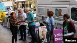 Campaign volunteers address a voter at the entrance to an Australian Electoral Commission early voting center ahead of the national election, in the Central Business District of Sydney, May 17, 2022. 