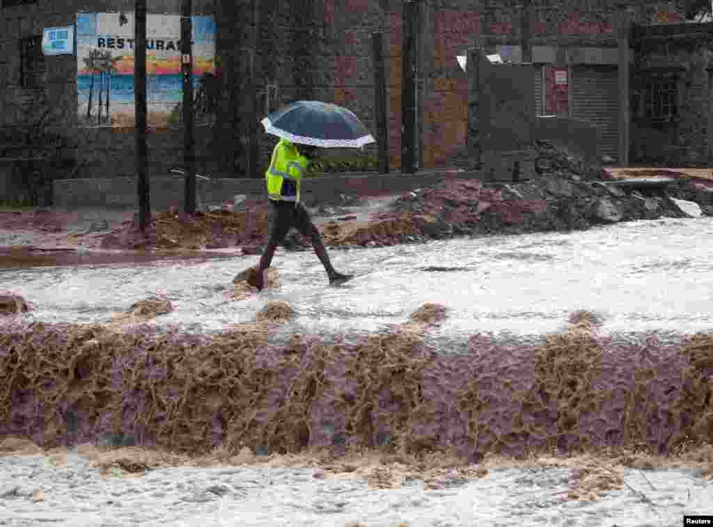 A man crosses a flooded bridge, caused by heavy rains, in kwaNdengezi near Durban, South Africa.