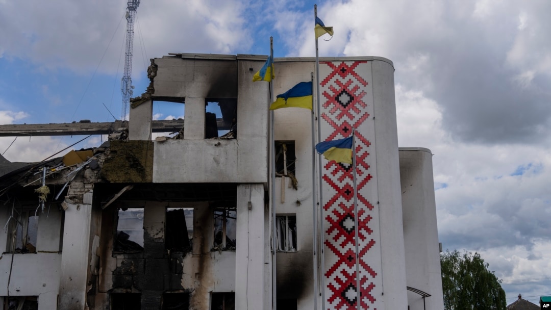 Ukrainian flags flutter outside a destroyed cultural center in Derhachi, eastern Ukraine, May 15, 2022. A Russian airstrike destroyed the venue on May 12.