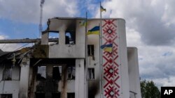 Ukrainian flags flutter outside a destroyed cultural center in Derhachi, eastern Ukraine, May 15, 2022. A Russian airstrike destroyed the venue on May 12.