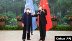 In this photo released by Xinhua News Agency, Chinese Foreign Minister Wang Yi, right, poses for photo with the United Nations High Commissioner for Human Rights Michelle Bachelet in Guangzhou, in southern China's Guangdong province, May 23, 2022.