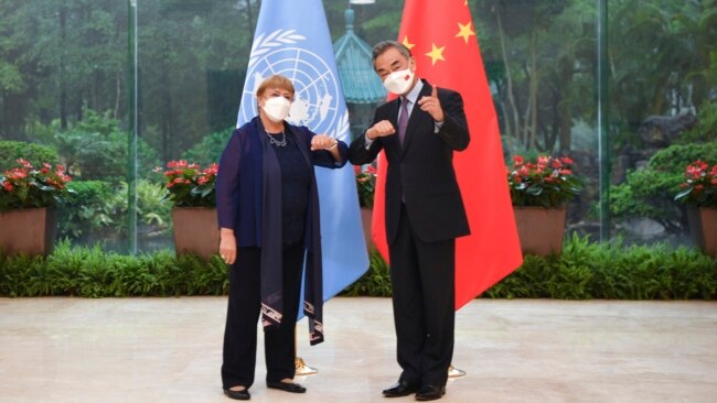 In this photo released by Xinhua News Agency, Chinese Foreign Minister Wang Yi, right, poses for photo with the United Nations High Commissioner for Human Rights Michelle Bachelet in Guangzhou, in southern China's Guangdong province, May 23, 2022.