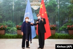 FILE - In this photo released by Xinhua News Agency, Chinese Foreign Minister Wang Yi, right, poses for photo with the United Nations High Commissioner for Human Rights Michelle Bachelet in Guangzhou, in southern China's Guangdong province, May 23, 2022.