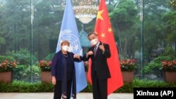 In this photo released by Xinhua News Agency, Chinese Foreign Minister Wang Yi, right, poses for photo with the United Nations High Commissioner for Human Rights Michelle Bachelet in Guangzhou, in southern China's Guangdong province, May 23, 2022.