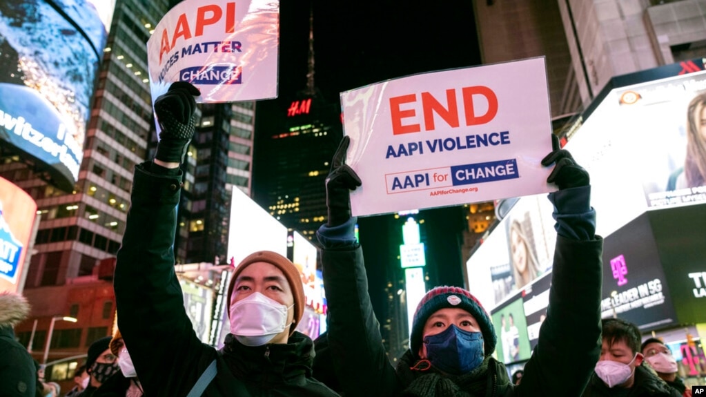 资料照片：2022年1月18日，人们在纽约时报广场举着支持亚裔太平洋岛民社区的标语，参加纪念地铁袭击事件受害者米歇尔·阿丽莎·戈 (Michelle Alyssa Go) 的烛光守夜活动。（美联社照片）(photo:VOA)