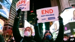 People hold signs in support of Asian American Pacific Islander communities while attending a candlelight vigil in honor of Michelle Alyssa Go, a victim of a recent subway attack, at Times Square on Jan. 18, 2022, in New York.