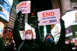 Las personas sostienen carteles en apoyo de las comunidades asiático-estadounidenses de las islas del Pacífico mientras asisten a una vigilia con velas en honor a Michelle Alyssa Go, víctima de un reciente ataque al metro, en Times Square el 18 de enero de 2022, en Nueva York.