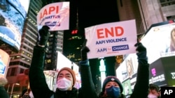 People hold signs in support of Asian American Pacific Islander communities while attending a candlelight vigil in honor of Michelle Alyssa Go, a victim of a recent subway attack, at Times Square on Jan. 18, 2022, in New York.